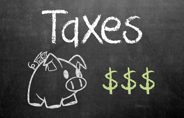 Chalkboard that reads "taxes" and has a drawing of a piggy bank